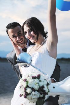 wedding sce of bride and groom just married couple on the beach ride white scooter and have fun