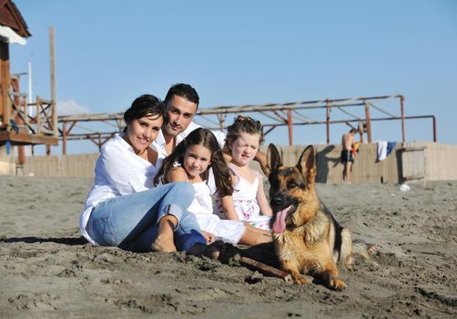 happy young family in white clothing have fun and play with beautiful dog at vacations on beautiful beach 