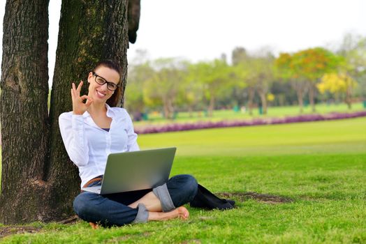 happy young student woman with laptop in city park study