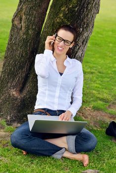 happy young student woman with laptop in city park study