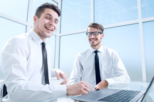 Two businessmen are sitting in the office and discussing the conclusion of a new deal