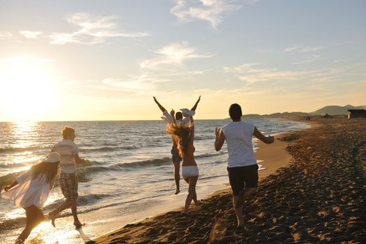 happy young people group have fun white running and jumping on beacz at sunset time