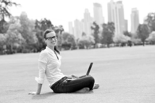 happy young student woman with laptop in city park study