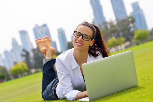 happy young student woman with laptop in city park study