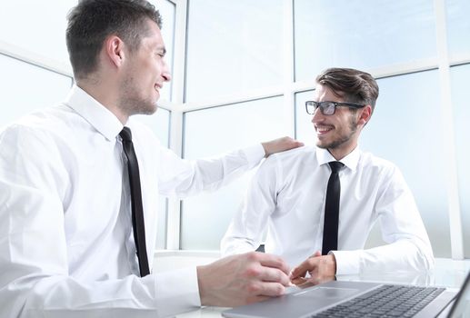 Two businessmen are sitting in the office and discussing the conclusion of a new deal