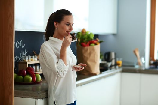 Happy woman drinking tea in the kitchen at home.