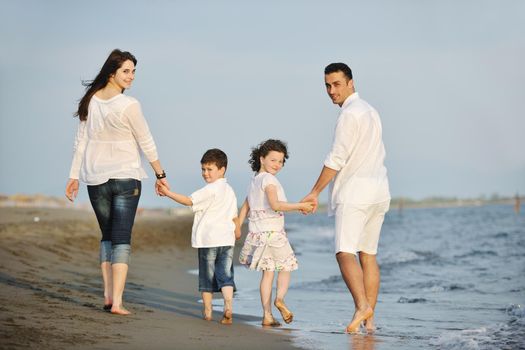 happy young family have fun on beach run and jump  at sunset