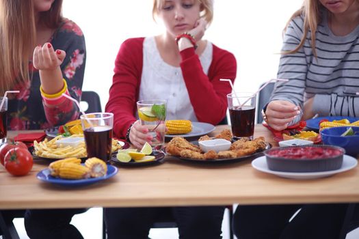 Top view of group of people having dinner together while sitting at wooden table. Food on the table. People eat fast food