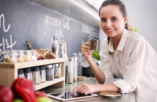 Portrait of young woman standing against kitchen background