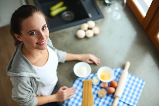 Beautiful woman cooking cake in kitchen standing near desk.