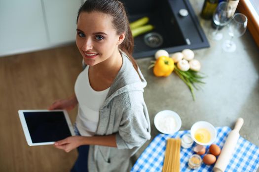 Woman baking at home following recipe on a tablet.