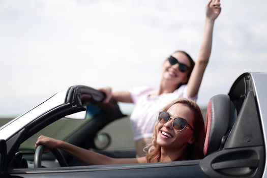 close up.two happy young women in a convertible car . fashionable lifestyle