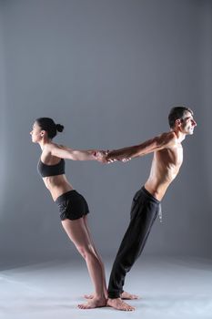 Young couple practicing acro yoga on mat in studio together. Acroyoga. Couple yoga. Partner yoga