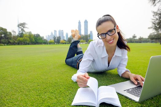 happy young student woman with laptop in city park study