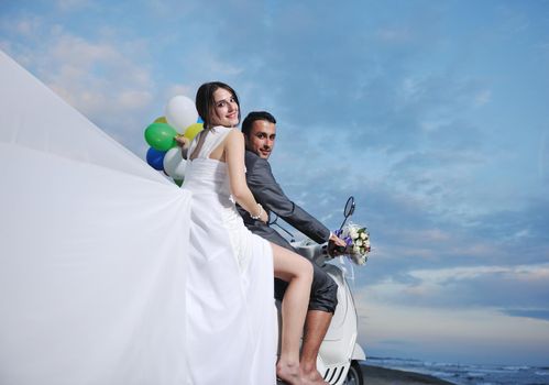 wedding sce of bride and groom just married couple on the beach ride white scooter and have fun