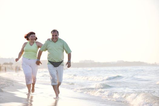 happy senior mature elderly people couple have romantic time on beach at sunset 