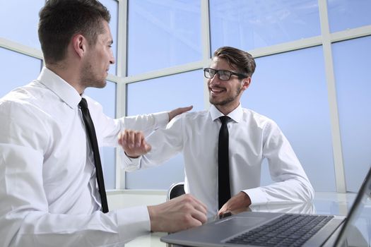 Two businessmen are sitting in the office and discussing the conclusion of a new deal