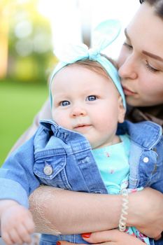 Closeup young caucasian mother kissing little daughter wearing jeans jacket. Concept of motherhood and children.