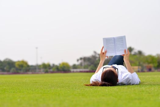 Young student woman reading a book and study in the park