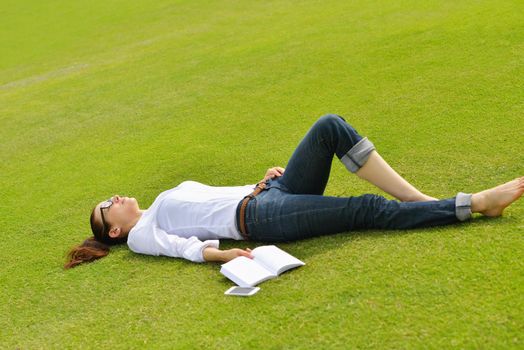 Young student woman reading a book and study in the park