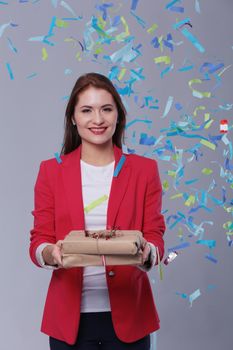 Beautiful happy woman with gift box at celebration party with confetti . Birthday or New Year eve celebrating concept.