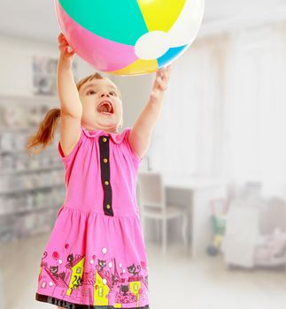 Emotional girl raised her hands up she catches the ball. Close-up.In the background children's room, where the shelves are containers with toys, and at the window a large white Desk.