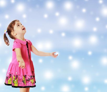 Adorable little girl with pigtails on the head , in a pink dress. The girl was looking at the top turned sideways to the camera.On new year or Christmas blue background with white big stars.
