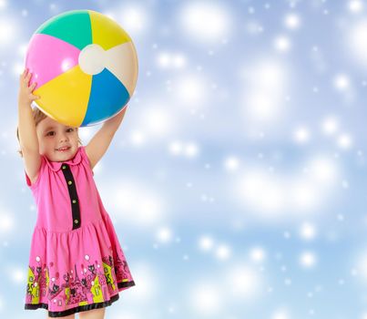 Caucasian little girl in a short pink dress , holding up a big ball.On new year or Christmas blue background with white big stars.