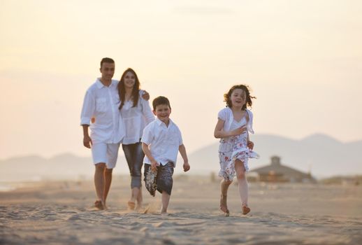 happy young family have fun on beach run and jump  at sunset