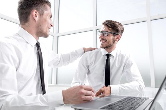 Two businessmen are sitting in the office and discussing the conclusion of a new deal