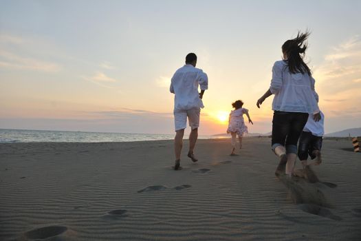 happy young family have fun on beach run and jump  at sunset