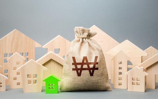 South korean won money bag and a city of house figures. City municipal budget. Buying real estate, fair price. Investments. Cost of living. Property tax. Development, renovation of buildings.