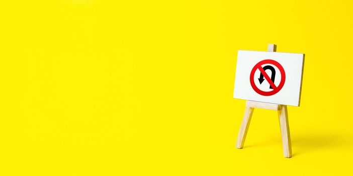 Easel with no turning back traffic sign on a yellow background. Assertiveness and striving, moving forward without retreating. Go to the goal, don't stop. Finish things. There is no way back.