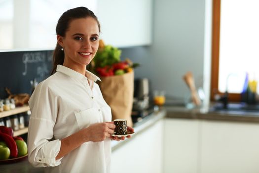 Happy woman drinking tea in the kitchen at home.