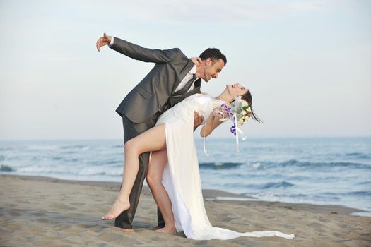 happy just married young couple celebrating and have fun at beautiful beach sunset