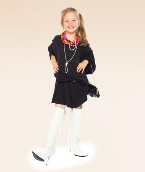 Fashionable little girl in a black dress and long boots on high sole.