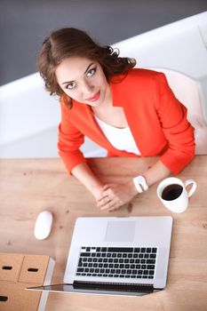 Attractive woman sitting at desk in office, working with laptop