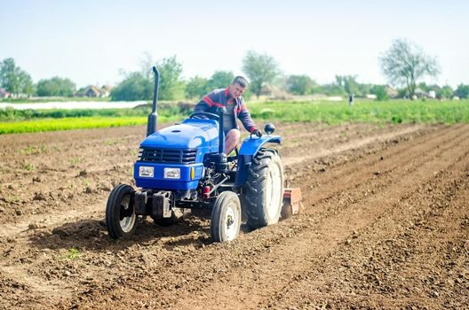 A farmer on a tractor cultivates a farm field. Soil milling, crumbling and mixing. Loosening the surface, cultivating the land for further planting. Agriculture, growing organic food vegetables