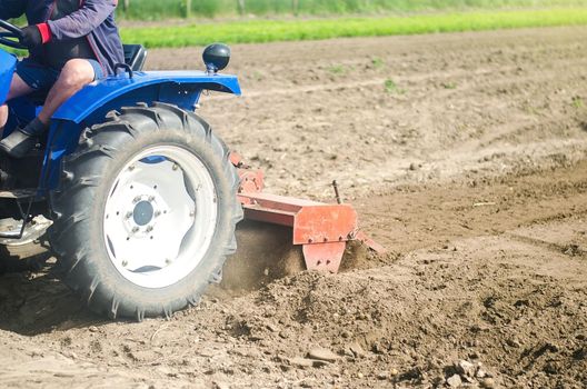 Tractor with milling machine loosens, grinds and mixes soil. Farming and agriculture. Loosening the surface, cultivating the land for further planting. Cultivation technology equipment