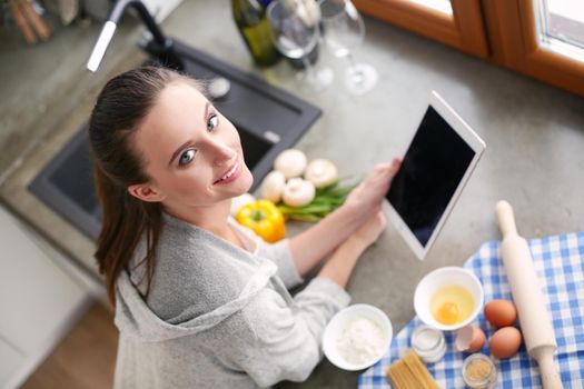 Beautiful woman cooking cake in kitchen standing near desk