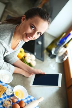 Woman baking at home following recipe on a tablet.