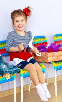 Happy little girl sitting on a chair . Next to it lay a box with new clothes in which she will dress up.