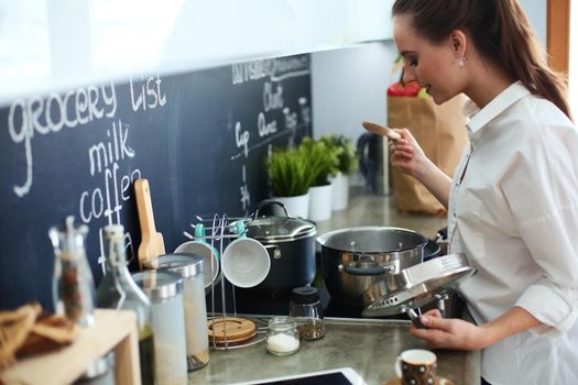 Young woman standing by the stove in the kitchen .