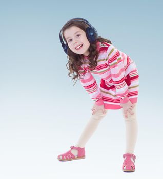 Cheerful little girl in big black headphones.