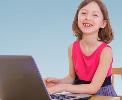 Smiling blonde girl working for a desktop computer.