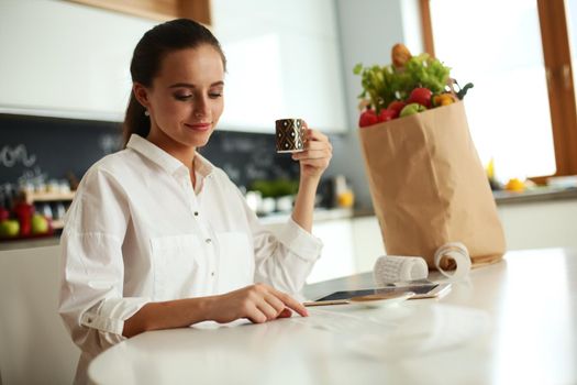 Young woman planning expenses and paying bills on her kitchen.