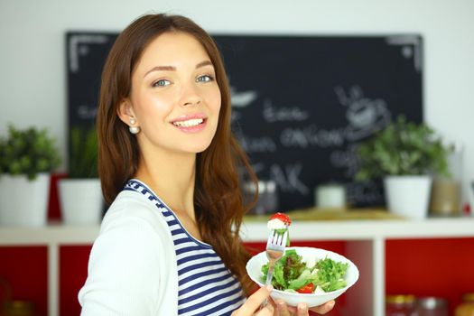 Young woman eating salad and holding a mixed .