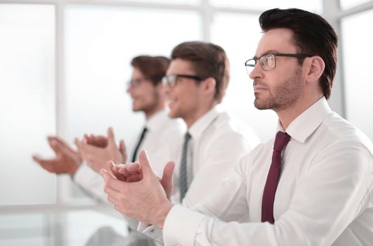 group of business people applauding sitting at the office table.success concept