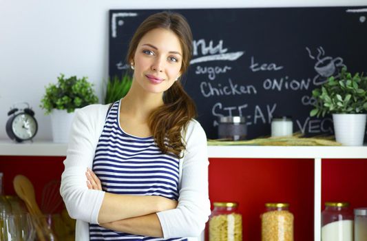 Young woman standing near desk in the kitchen.