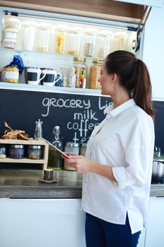 Young woman using a tablet computer to cook in her kitchen .